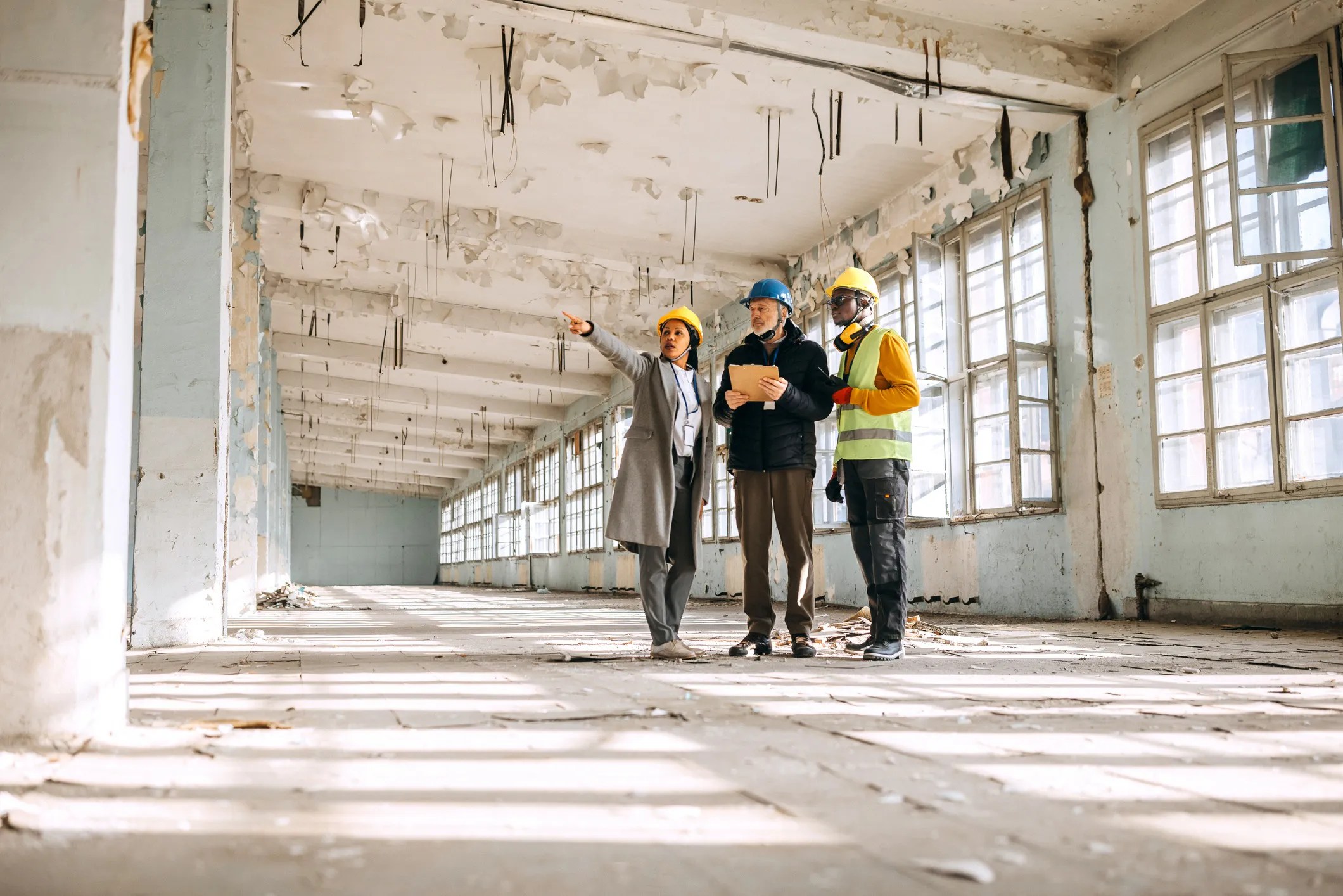 Engineers and safety professionals inspecting a building structure to identify potential hazards, evaluate stability, and assure compliance with safety standards.