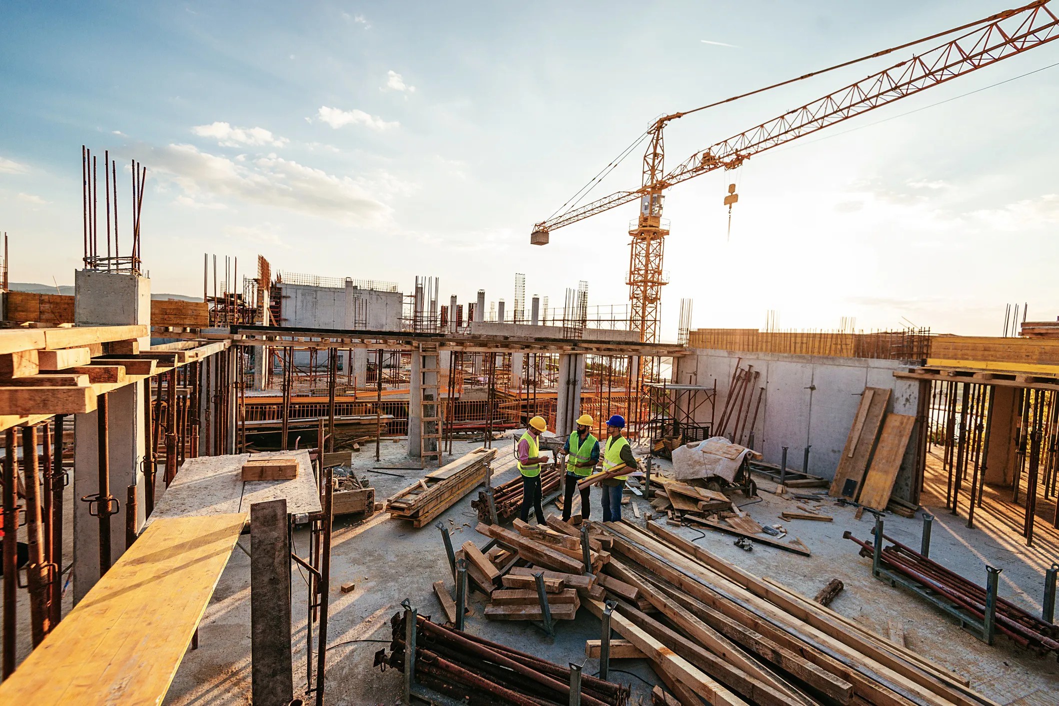 Structural engineers reviewing building plans at an active construction site to ensure structural reliability, safety, and compliance with ISO 22111:2019 design principles.