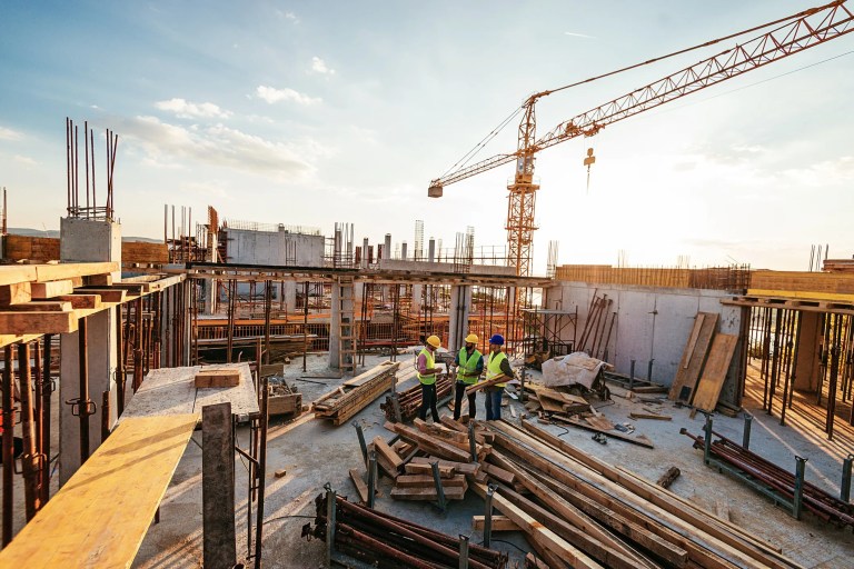 Structural engineers reviewing building plans at an active construction site to ensure structural reliability, safety, and compliance with ISO 22111:2019 design principles.