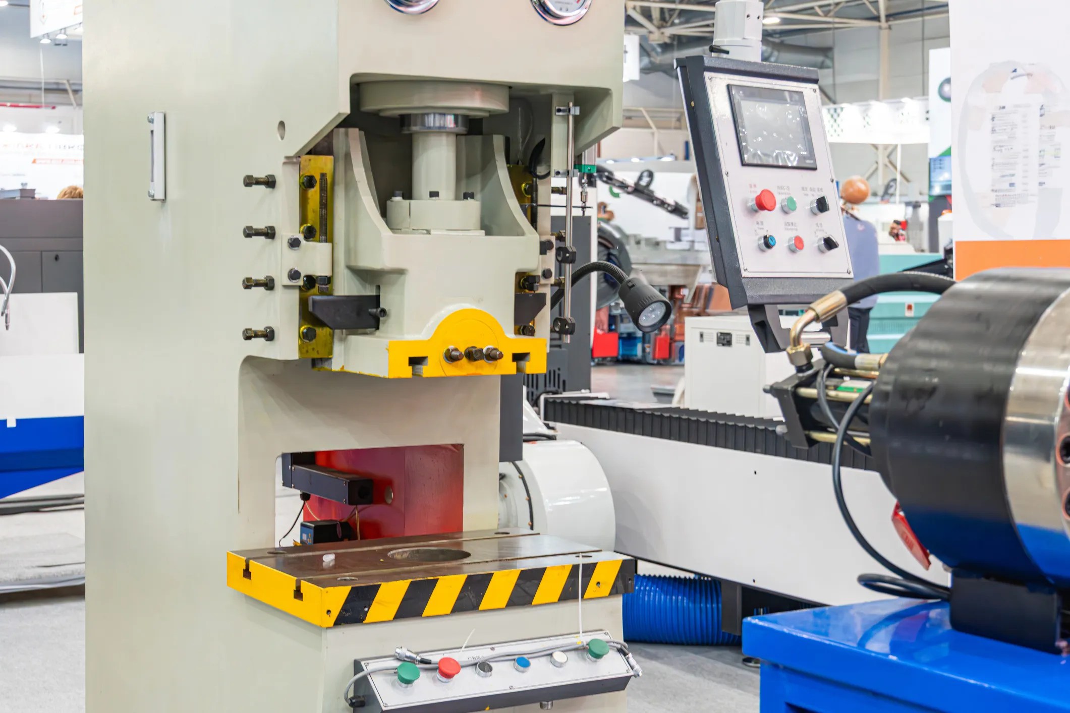 Industrial hydraulic power press in a manufacturing facility with machine guarding and safety controls, adhering to ANSI B11.2-2013 (R2020), protecting operators during metal forming operations.