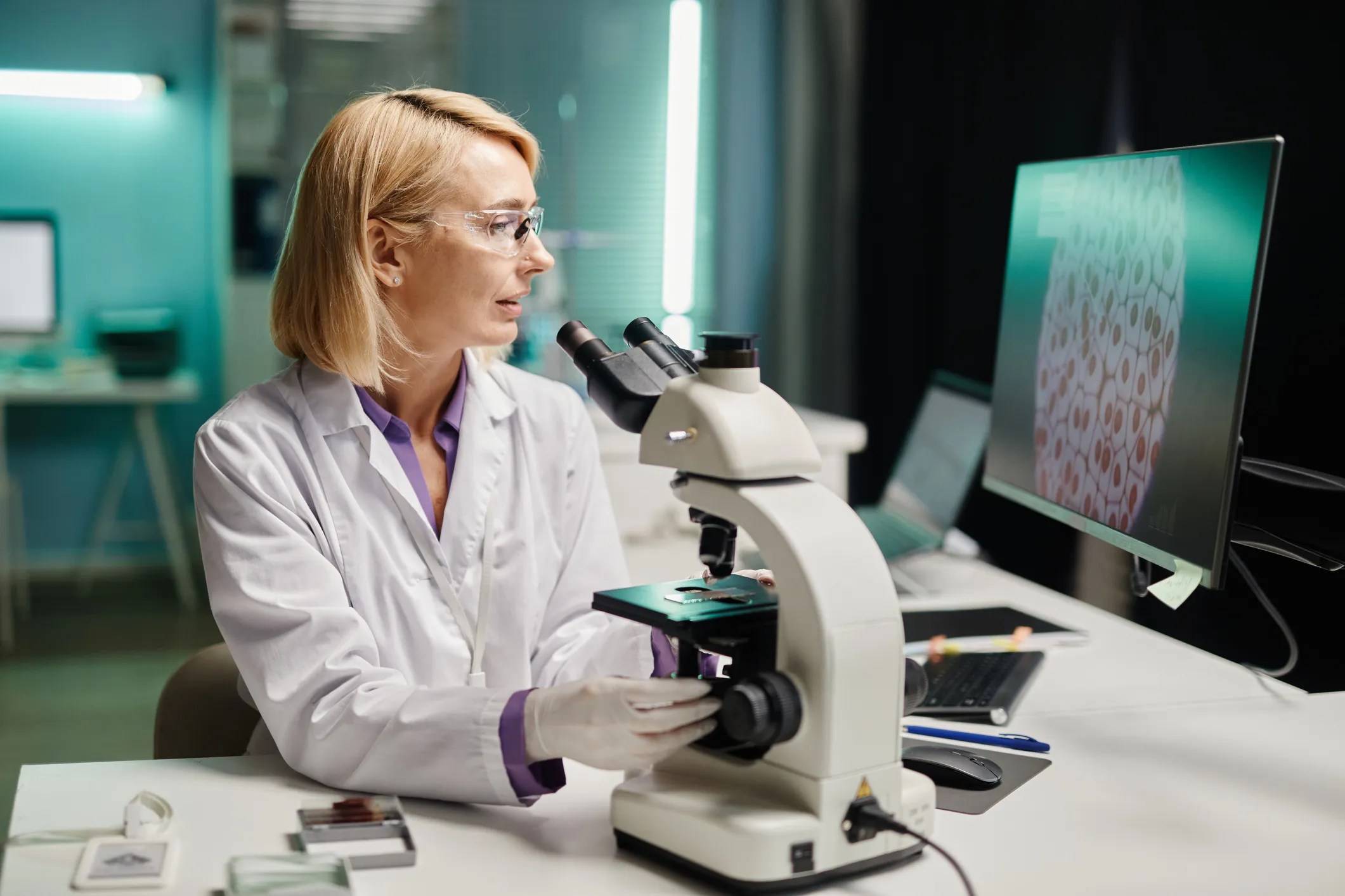 Laboratory professional examining body fluid cells under a microscope following CLSI H56-A guidance.