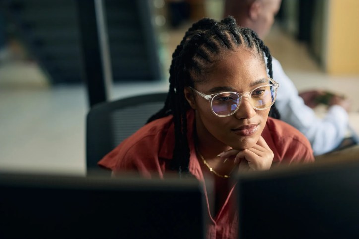 Professional with AI competency looking into computer screen to get to work.