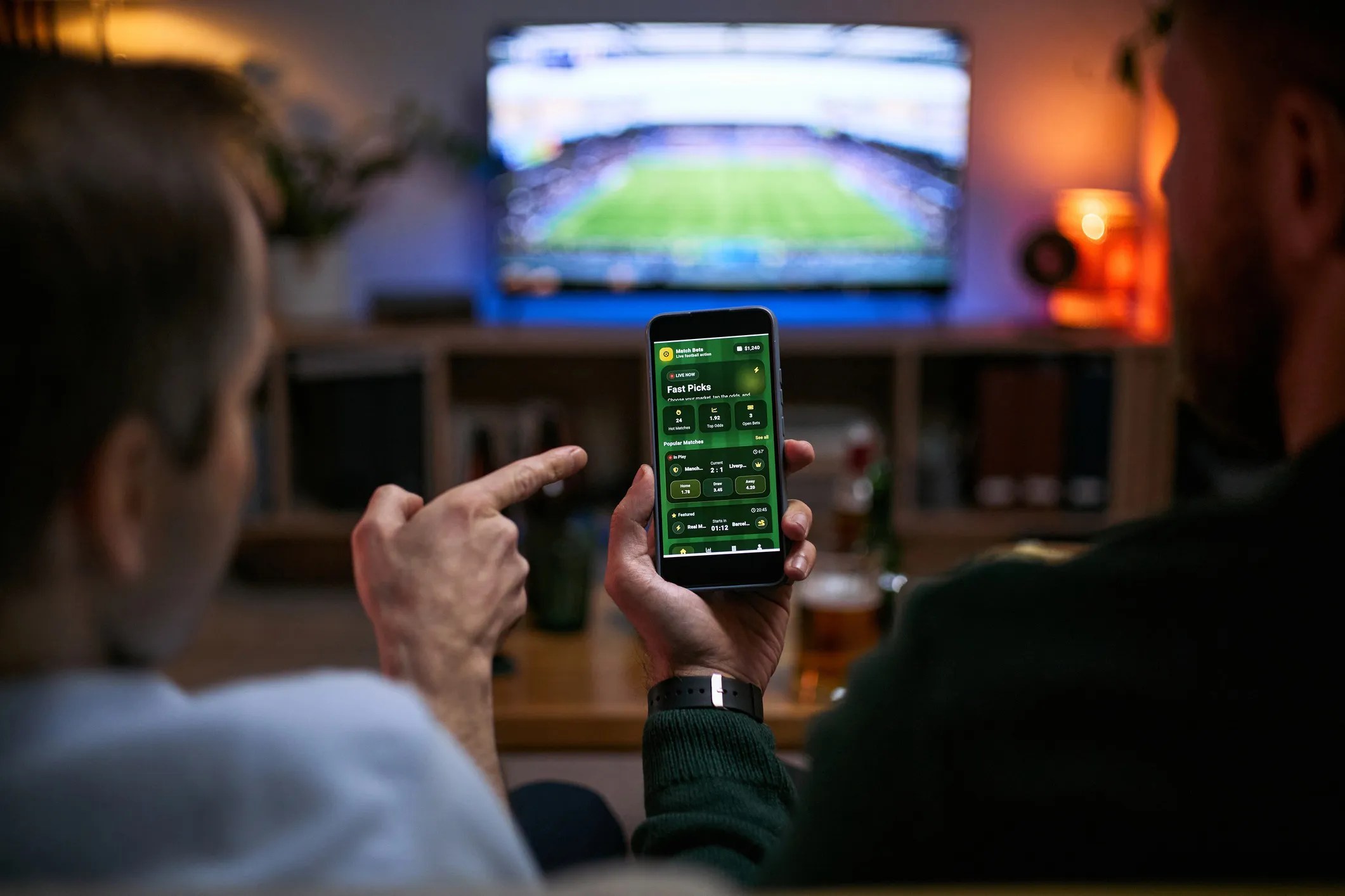 Two friends watching a live sports game and viewing real-time sports statistics on an iPhone, highlighting AI-powered fan engagement and ISO/IEC 42001:2023 AI management systems.